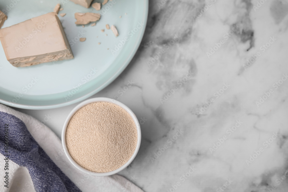 Granulated and compressed yeast on white marble table, flat lay. Space for text Granulated and compressed yeast on white marble table, flat lay. Space for text