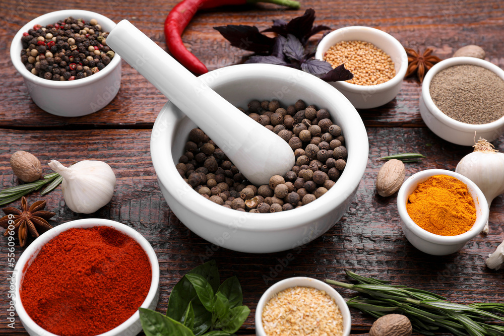 Mortar and different spices on wooden table, above view Mortar and different spices on wooden table, above view