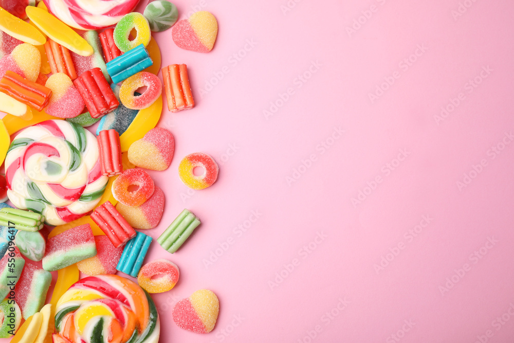 Many different jelly candies and lollipops on pink background, flat lay. Space for text Many different jelly candies and lollipops on pink background, flat lay. Space for text
