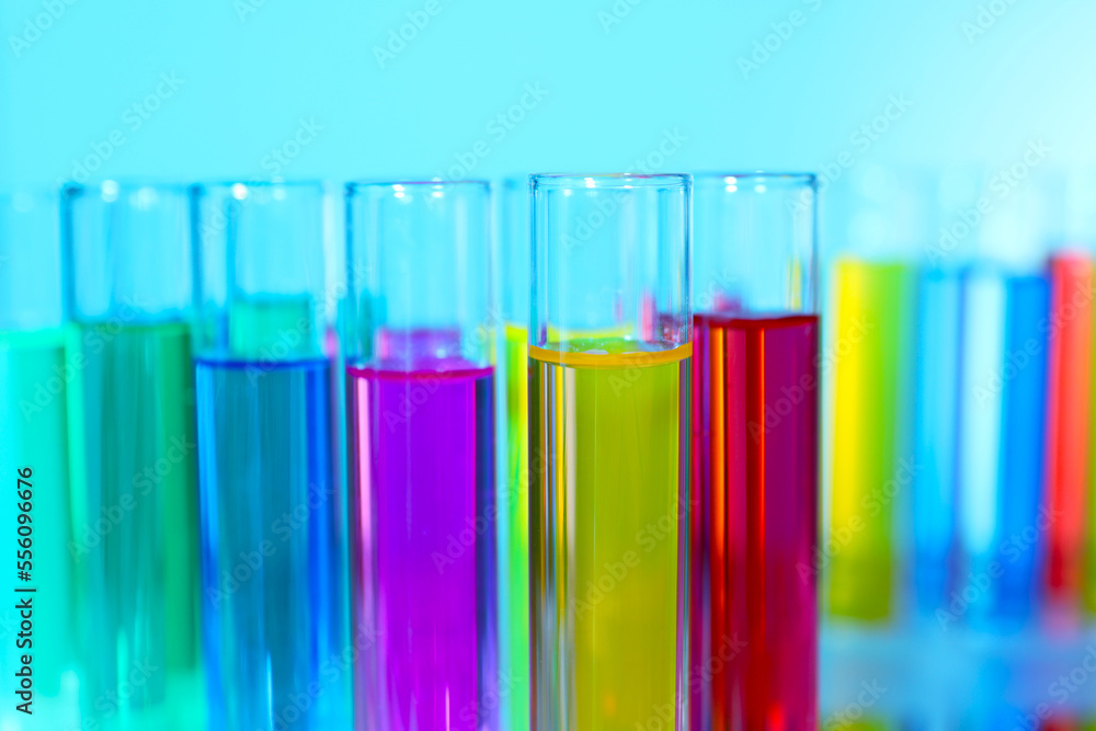 Many test tubes with colorful liquids on blurred background, closeup Many test tubes with colorful liquids on blurred background, closeup