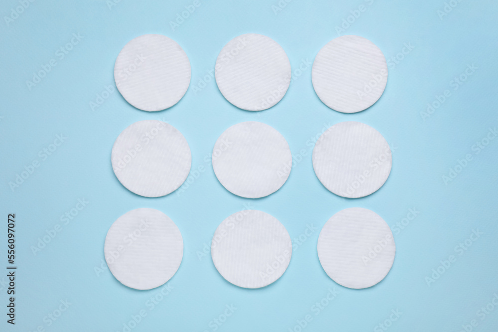 Many cotton pads on light blue background, flat lay Many cotton pads on light blue background, flat lay