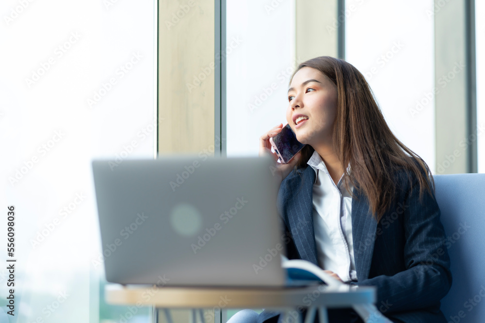 Businesswoman sitting and reading a book by the window of the office. Used in marketing business media, insurance, life insurance, finance Businesswoman sitting and reading a book by the window of the office. Used in marketing business media, insurance, life insurance, finance