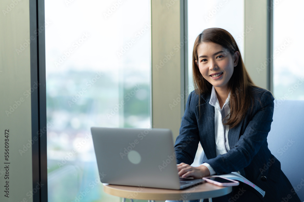 Businesswoman sitting and reading a book by the window of the office. Used in marketing business media, insurance, life insurance, finance Businesswoman sitting and reading a book by the window of the office. Used in marketing business media, insurance, life insurance, finance