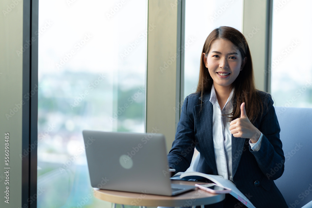 Businesswoman sitting and reading a book by the window of the office. Used in marketing business media, insurance, life insurance, finance Businesswoman sitting and reading a book by the window of the office. Used in marketing business media, insurance, life insurance, finance