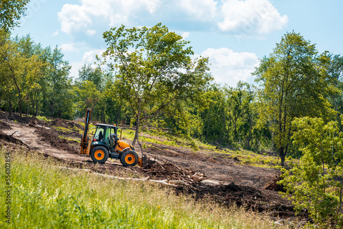 tractor works on landscaping, tree branches and debris