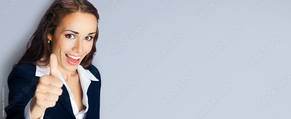 Businesswoman in confident black suit, showing thumbs up gesture, copy space place for text, advertising or slogan. Business concept photo. Gray color background Businesswoman in confident black suit, showing thumbs up gesture, copy space place for text, advertising or slogan. Business concept photo. Gray color background