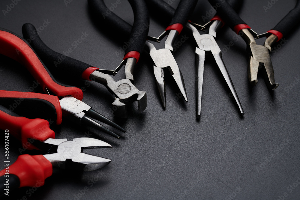 Fototapeta premium Set of different types of pliers and side cutters isolated on black background. Hand tools for repair, construction and maintenance