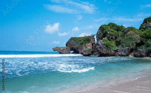 White sand, a blue sea, a bright blue sky, and stunning waves can all be seen in this daytime photo of Siung beach. photo