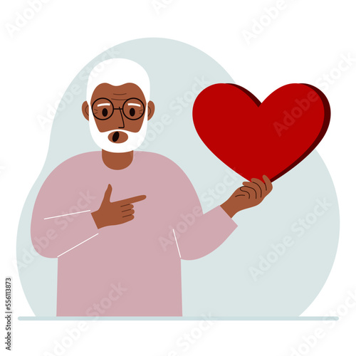 A man holds a big red heart in his hand. The concept of volunteering, romantic relationship or love.