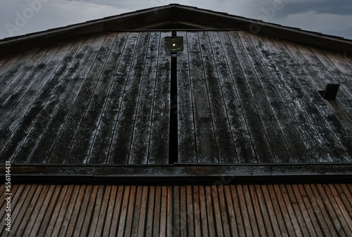 Fassade eines rustikalen und mystisch sowie düster wirkenden Holzhauses mit Bewegungsmelder und Nistkasten aus dunklen und verwitterten Brettern und Planken, aufgenommen aus der Froschperspektive photo