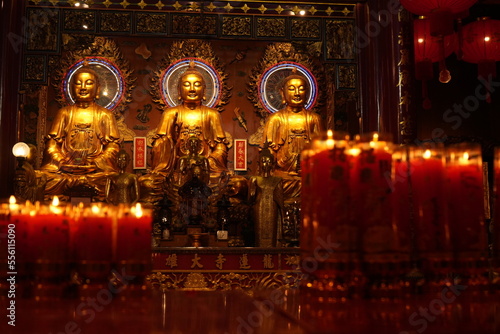 Bangkok : temple bouddhiste dans le quartier chinois avec de nombreux lampions rouges et autels où brulent des bougies devant des statues de bouddhas dorés 