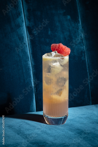 Obraz na płótnie Cocktail on blue background. Modern, stylish drink placed on velvet couch at the bar, night club or restaurant. Refreshing alcoholic beverage with grapefruit and gin in highball glass. Copy space w salonie