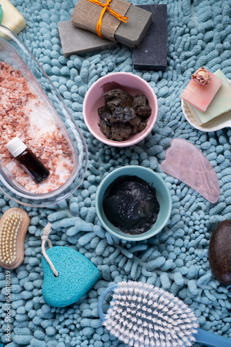 natural healing spa set with salt, healing mud and soap on blue bath mat. flay lay
