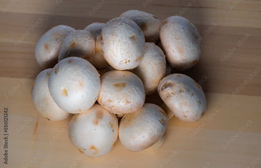 champignon mushrooms on a wooden table in dim light champignon mushrooms on a wooden table in dim light
