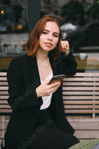 Young woman uses the phone at the street cafe