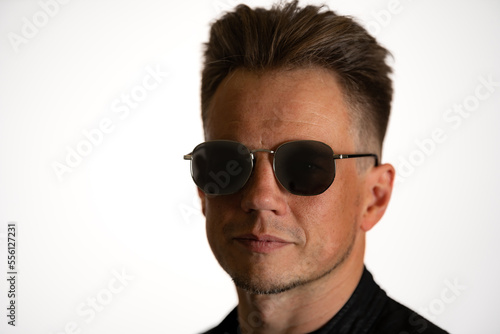 Portrait of handsome male. Sexy stylish man dressed in a leather jacket and sunglasses. Fashion hipster male isolated on white background in studio