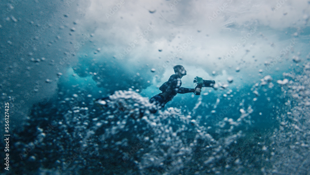 Underwater view of the surf photographer diving under the wave with camera