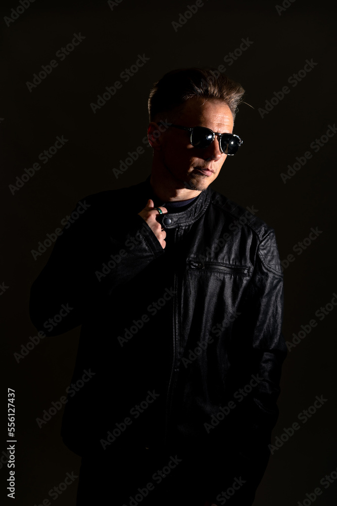 Portrait of handsome male. Sexy stylish man dressed in a leather jacket and sunglasses. Fashion hipster male isolated on grey background in studio Portrait of handsome male. Sexy stylish man dressed in a leather jacket and sunglasses. Fashion hipster male isolated on grey background in studio