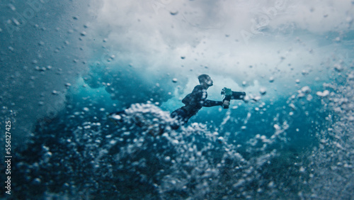 Underwater view of the surf photographer diving under the wave with camera