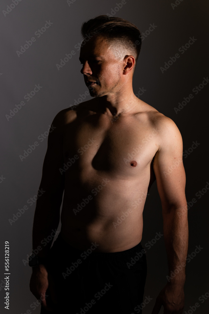 Fototapeta premium Sexy portrait of muscular handsome topless male isolated against a grey background