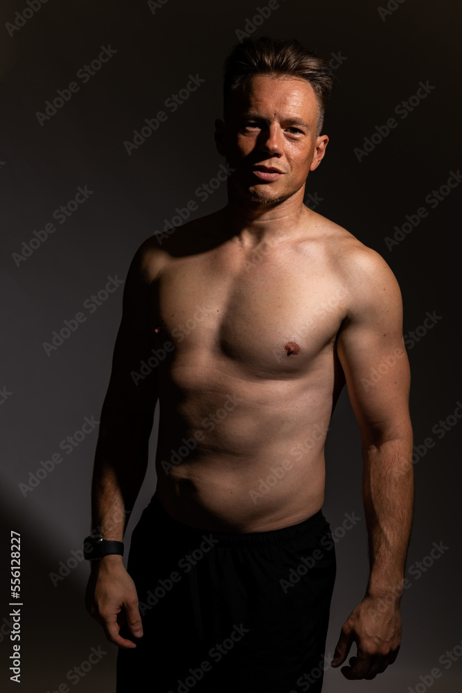 Sexy portrait of muscular handsome topless male isolated against a grey background