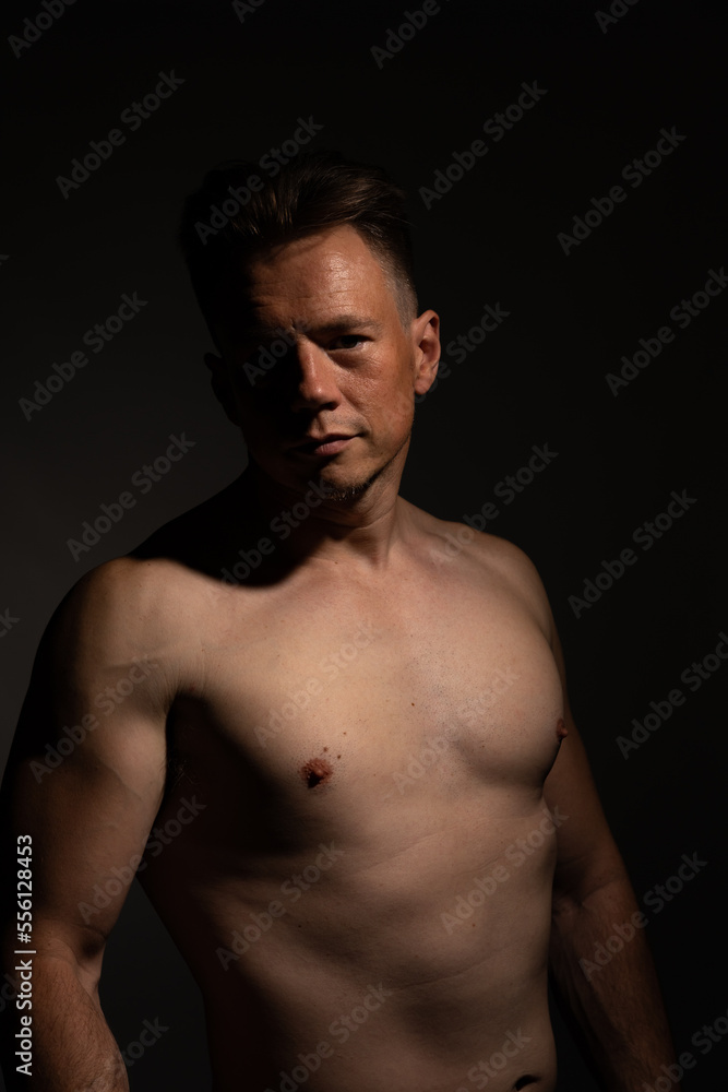 Sexy portrait of muscular handsome topless male isolated against a black background Sexy portrait of muscular handsome topless male isolated against a black background