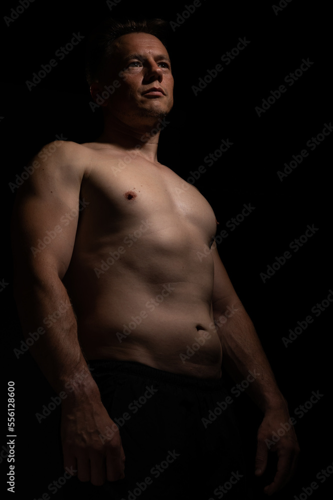 Sexy portrait of muscular handsome topless male isolated against a black background