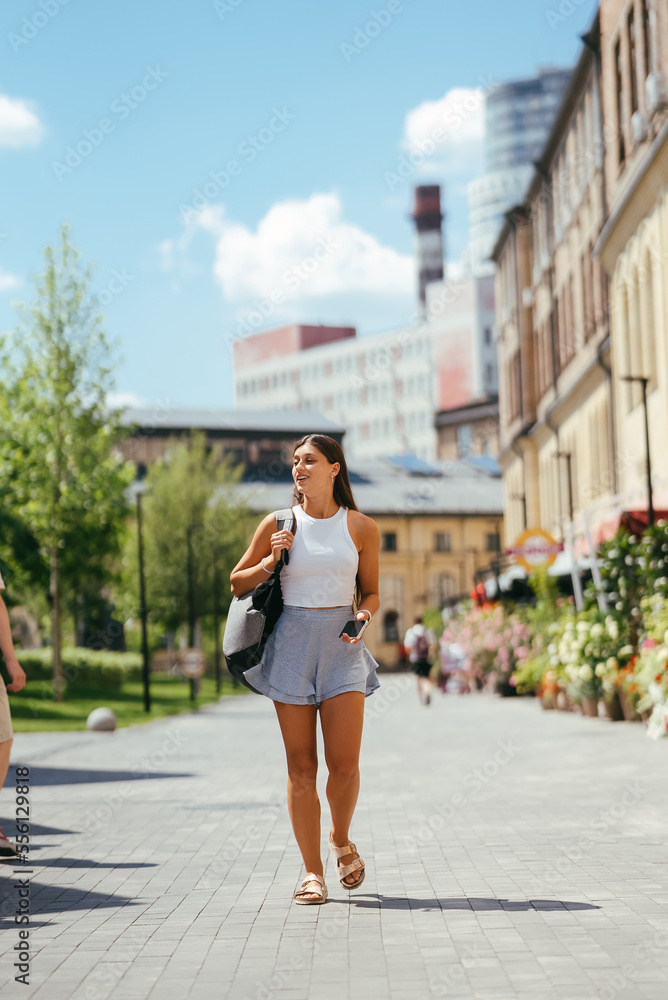 Young woman with backpack walks around the city.