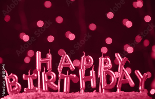 Minimalistic background with viva magenta candles without fire letters in cake close up. Garland of pink bokeh circles at back. Birthday celebration concept. Happy birthday card.