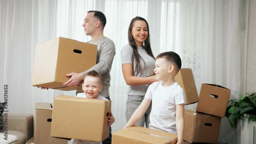 Family explores new apartment and gets ready to move carrying packages. Preschooler boy and junior schoolboy enjoy moving into new house Family explores new apartment and gets ready to move carrying packages. Preschooler boy and junior schoolboy enjoy moving into new house