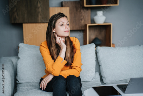 Φωτογραφία Frustrated brunette hispanic woman in orange blouse sitting on cozy sofa with upset facial expression, tired frustrated girl after divorce failure mistake