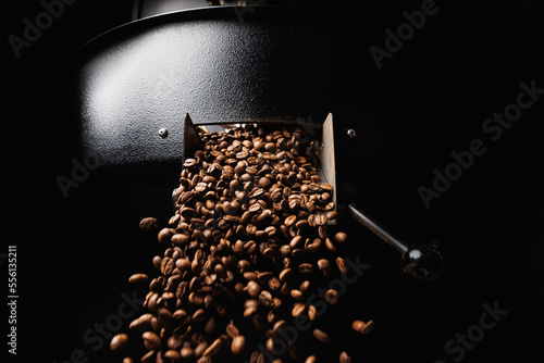 Foto Fresh roasted coffee beans move on professional mixing roaster machines, dark ba