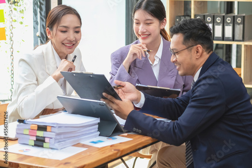 Asian business team consists of marketing staff. accountant and financial officer Help each other analyze company profits using tablets. calculator Laptop computers, graph paper, and corporate pens.