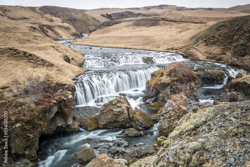La parte superiore di Skógafoss, con rocce nel corso d'acqua e salti d'acqua con vista verso l'entroterra islandese photo