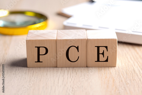 PCE- personal consumption expenditure on wooden cubes with magnifier and calculator, financial concept background photo
