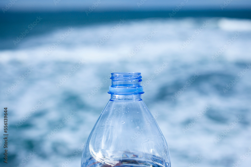 Close up view of a transparent open plastic bottle without a cap with selective focus and defocused natural sea background. Plastic recycling concept. plastic bottle without a screw cap. Close up view of a transparent open plastic bottle without a cap with selective focus and defocused natural sea background. Plastic recycling concept. plastic bottle without a screw cap.