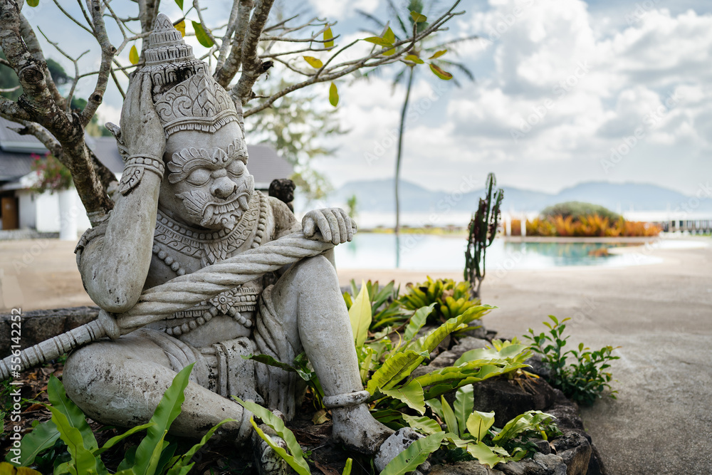 Statue in Balinese or Asian style made of stone in tropical greenery against the backdrop of a seascape with islands. Statue in Balinese or Asian style made of stone in tropical greenery against the backdrop of a seascape with islands.