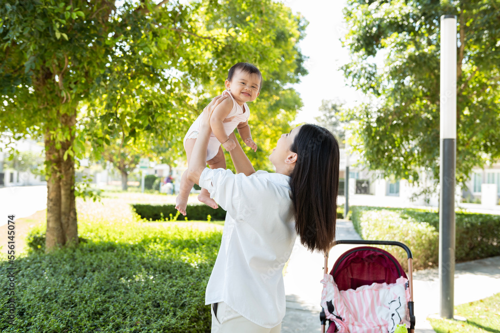 Beautiful mom holding a baby girl in her arms outdoor in sunshine day. Beautiful mom holding a baby girl in her arms outdoor in sunshine day.