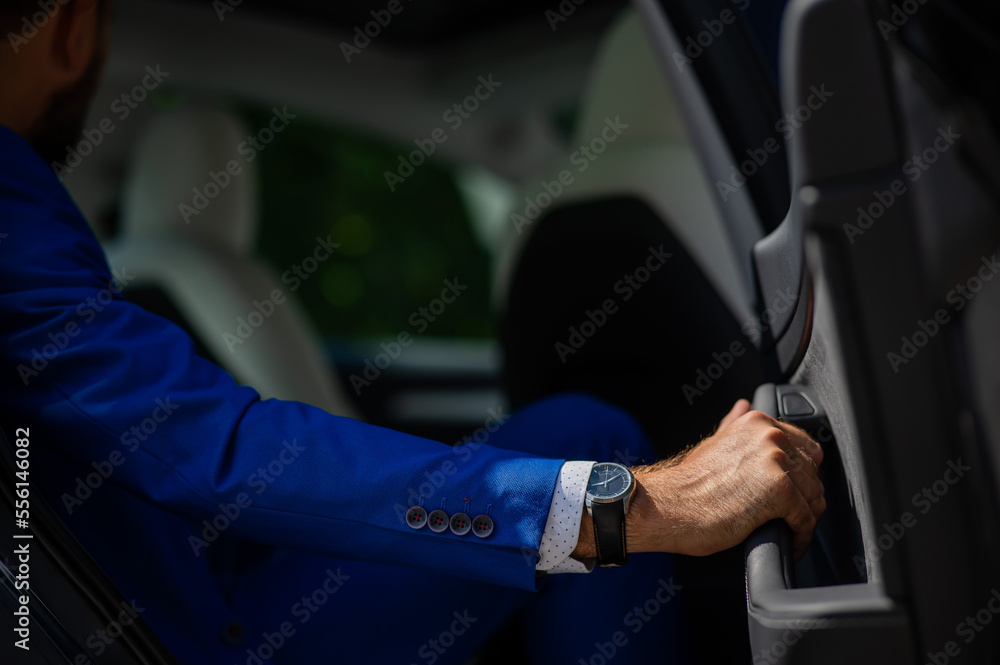 A man in a blue suit opens the car door. Close-up of a man's hand with an expensive watch. A man in a blue suit opens the car door. Close-up of a man's hand with an expensive watch.