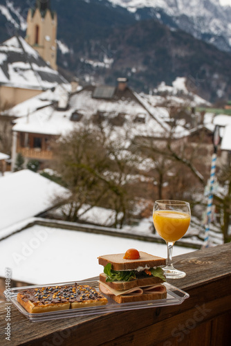 breakfast on the balcony in winter with orange juice sandwich and pancake with hazelnut cream and european alps in the background