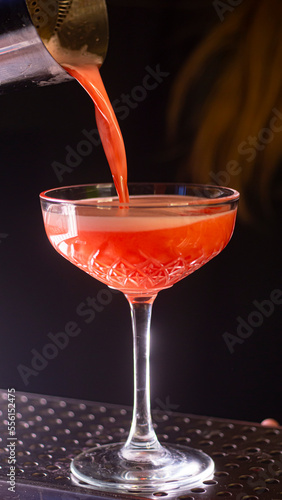 Red cocktail is poured into a glass