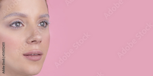 A girl with blue eyes and winter make-up  snowy eyelashes and eyebrows. Artistic close up photo Pink backround .Space for text on the right Fashion  beauty  makeup  cosmetics  beauty salon  style