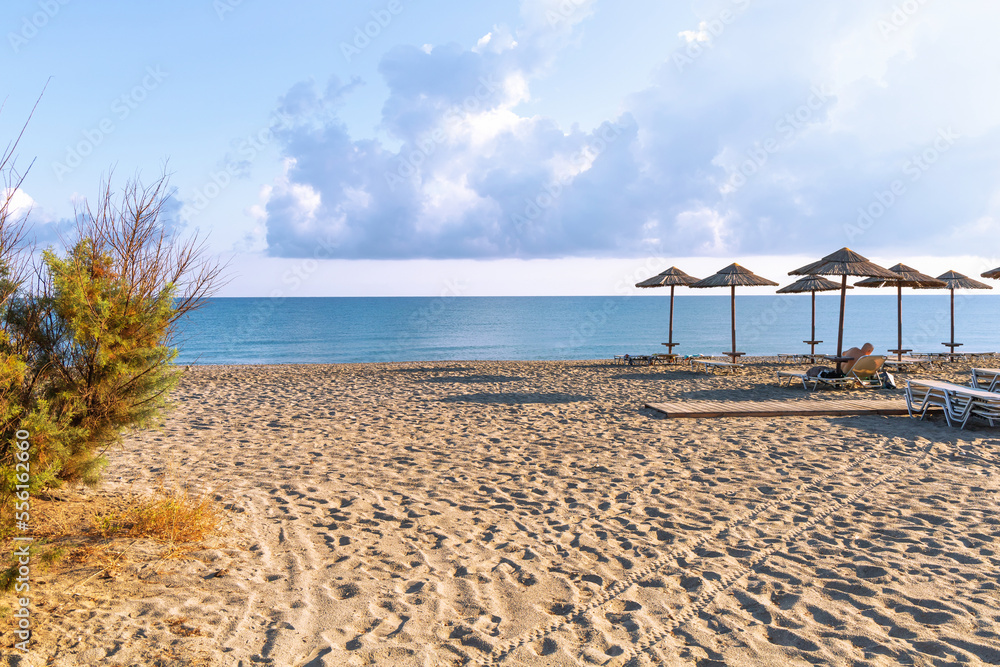 Fototapeta premium Empty beach with sun loungers and umbrellas in the early morning on a sunny day on the Crete island Greece. . High quality photo