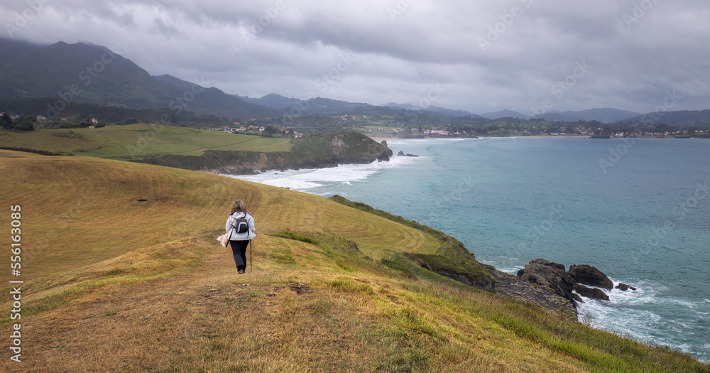 Woman Hiking a Coastal Path to Arenal de Moris Beach in Asturias, Spain