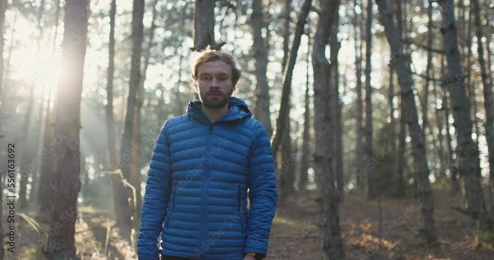 Portrait of a trail runner man standing in the woods. Sun shining through trees in a forest on sunset. Slowmotion video. Portrait of a trail runner man standing in the woods. Sun shining through trees in a forest on sunset. Slowmotion video.