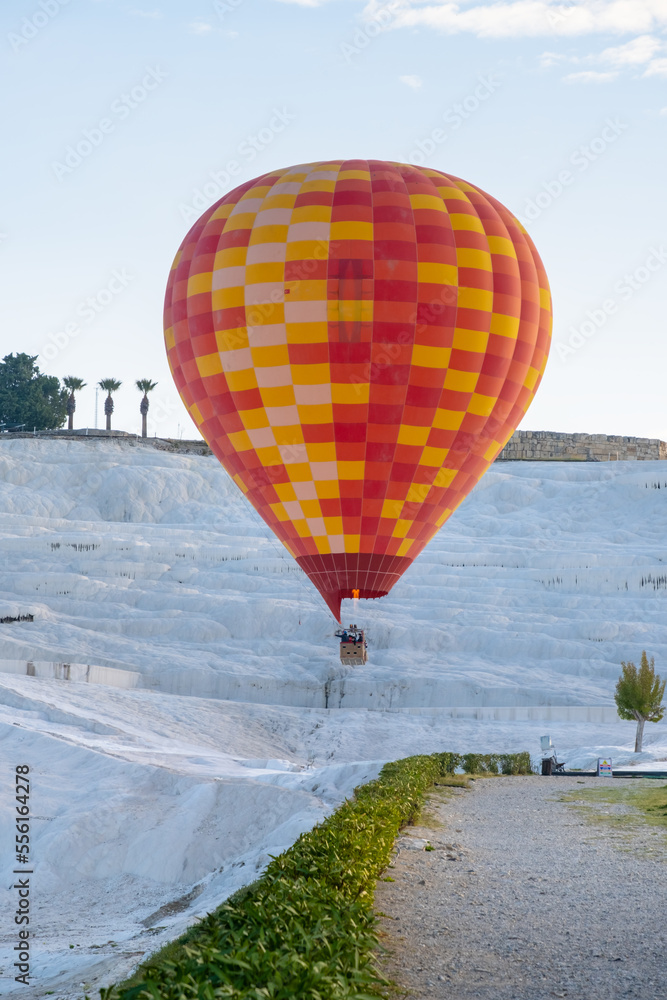 Hot air balloon flying over Travertine pools limestone terraces on a beautiful day. Pamukkale, Denizli, Turkey.