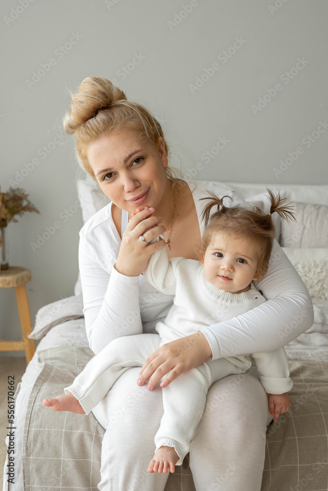 Portrait of young tired Mother and baby girl looking at camera in bedroom home. Child care, domestic life routine, healthy lifestyle. Exhausted woman take care about child and vertical Portrait of young tired Mother and baby girl looking at camera in bedroom home. Child care, domestic life routine, healthy lifestyle. Exhausted woman take care about child and vertical