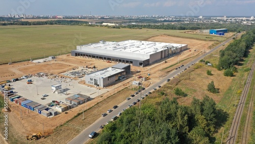 A construction site where a huge metal frame building of a medical equipment factory is being erected. The process of building a large hangar. Construction equipment, machinery, change houses. © Aerial Drone Master