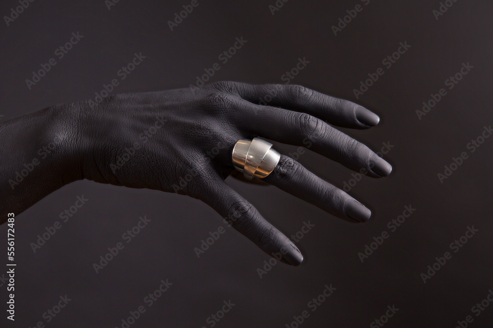Fototapeta premium Black woman's hand with Silver jewellery. Oriental Bracelets on a black painted hand. Silver Jewelry and luxury accessories on black background closeup.