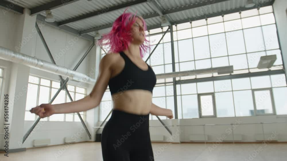 Woman exercising with a jumping rope, strengthening her upper body and legs. Close-up shot of a sportswoman doing intensive workout. High quality 4k footage Woman exercising with a jumping rope, strengthening her upper body and legs. Close-up shot of a sportswoman doing intensive workout. High quality 4k footage